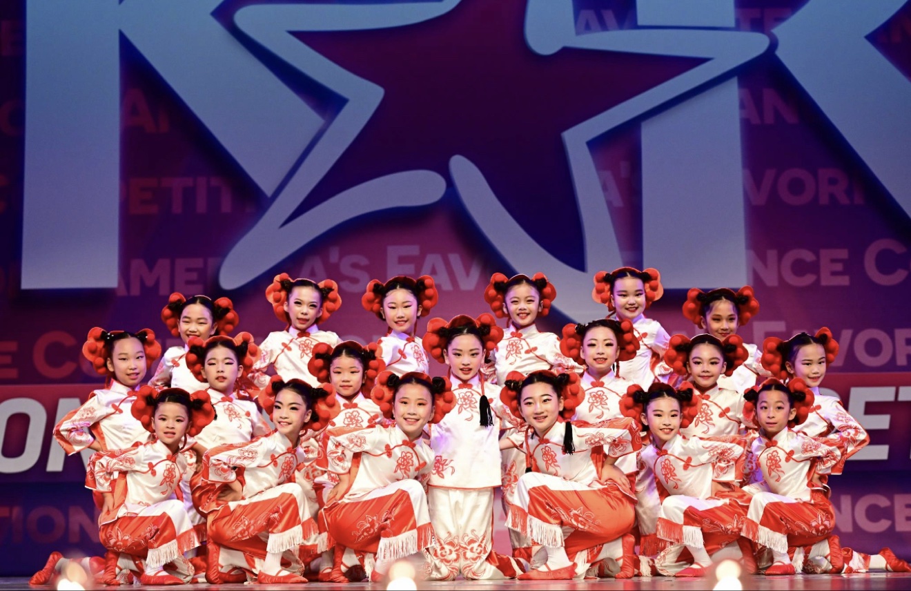 小学员身着红白中国风格服装在比赛舞台前合影